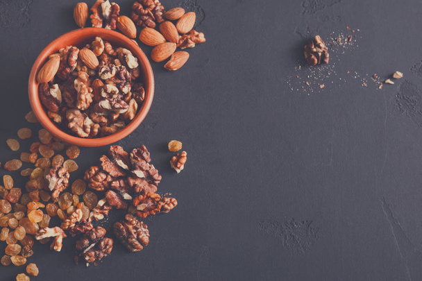Nuts and raisins on dark background, closeup, copy space - Фото, изображение