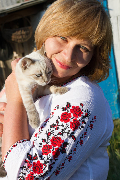 Happy woman with a cat relaxes. Woman looking at the camera. Middle-aged woman face close up. - Foto, Imagen