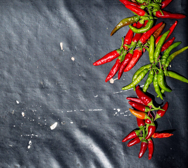 Red hot chili peppers buitenshuis. Rode en groene peper op donkere bestuur achtergrond - Foto, afbeelding