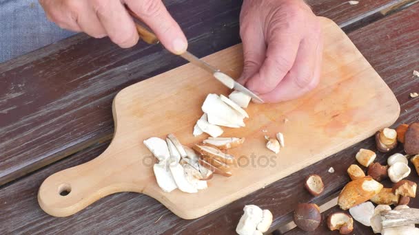 Chop fresh wild mushrooms. Close up shot of hands with a knife cutting mushrooms. Man hand carefully cut wild mushrooms on a kitchen wooden board  - Footage, Video