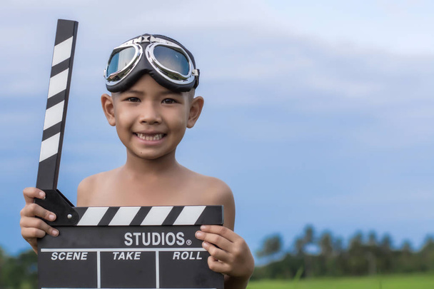 Kind film klepel bestuur spelen tegen zomer hemelachtergrond. Fi - Foto, afbeelding