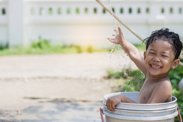Çocuk oyun ve su bir kova içinde oturan Bahçe, suda boğulmuş. Çocuk yetiştirme kavramı. - Fotoğraf, Görsel