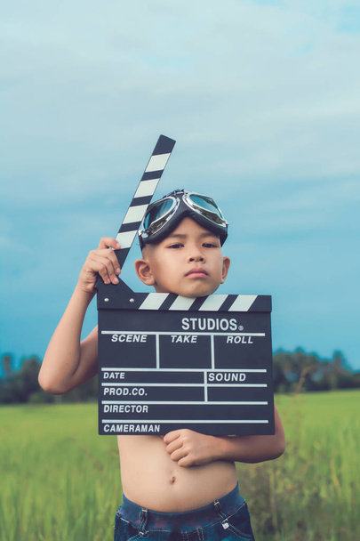 Kind spielt Filmklappbrett vor Sommerhimmel Hintergrund. fi - Foto, Bild