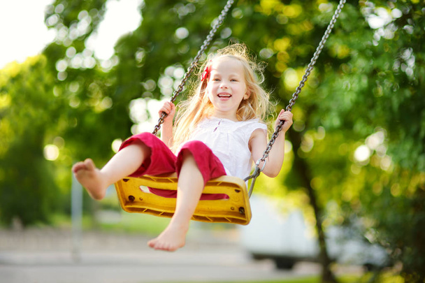 little girl swinging on playground - Foto, afbeelding