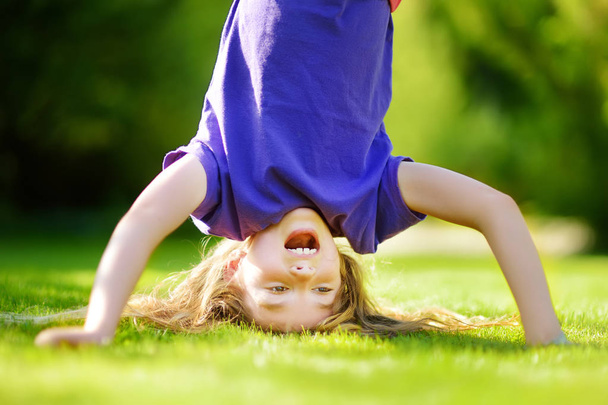girl playing head over heels on grass - Foto, afbeelding
