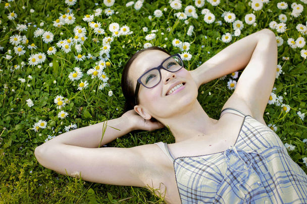 Hermosa chica tendida en un prado lleno de flores de margarita - soñar
 - Foto, imagen
