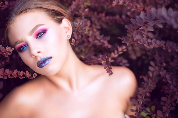 Portrait rapproché d'un beau modèle glam aux yeux bleus avec une mode brillante parfaite, posant dans des buissons d'épine-vinette pourpre avec l'air d'un détachement
.  - Photo, image