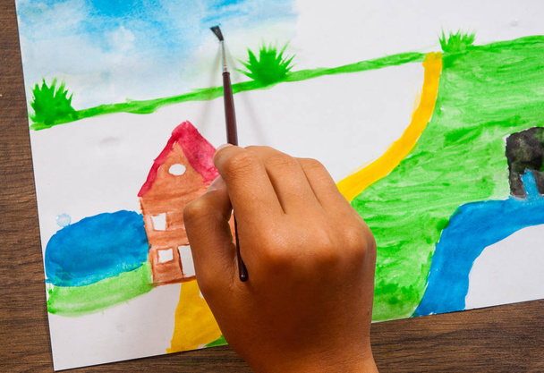 The child's hand draws a picture with watercolors. top view - Photo, Image