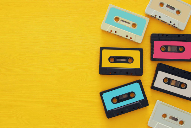Retro cassette tape collection over yellow wooden table. top view. copy space - Foto, Imagen