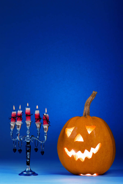 Halloween pumpkin with a candlestick, funny face face on a blue background. - Φωτογραφία, εικόνα