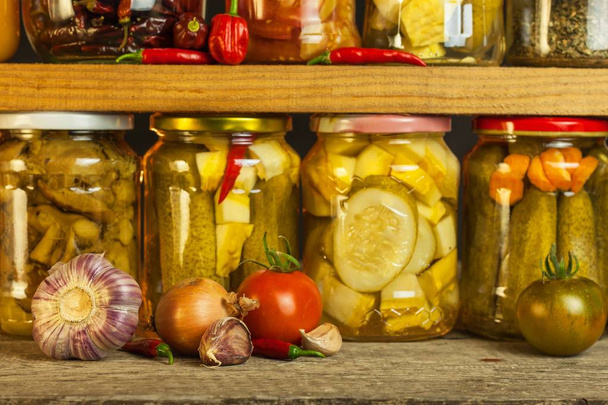 Jars with marinated food and organic raw vegetables. Preserved vegetables on wooden background. Various marinaded food. Life on a rural farm. - Foto, Imagem