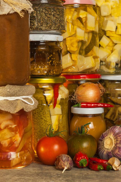Jars with marinated food and organic raw vegetables. Preserved vegetables on wooden background. Various marinaded food. Life on a rural farm. - Fotoğraf, Görsel