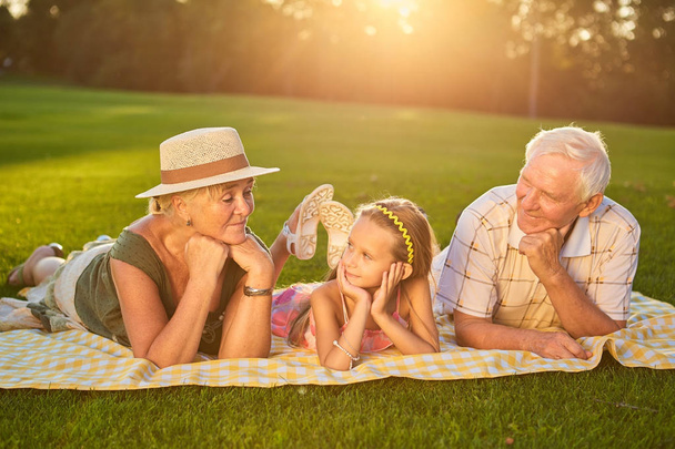 Grandparents with grandchild lying outdoors. - Photo, Image