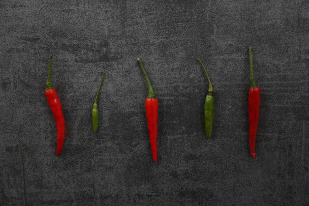 Red and green Chili pepper on dark rock background - Foto, afbeelding