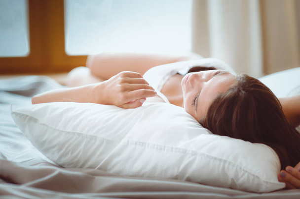 Beautiful brunette lying on bed at home - Fotó, kép