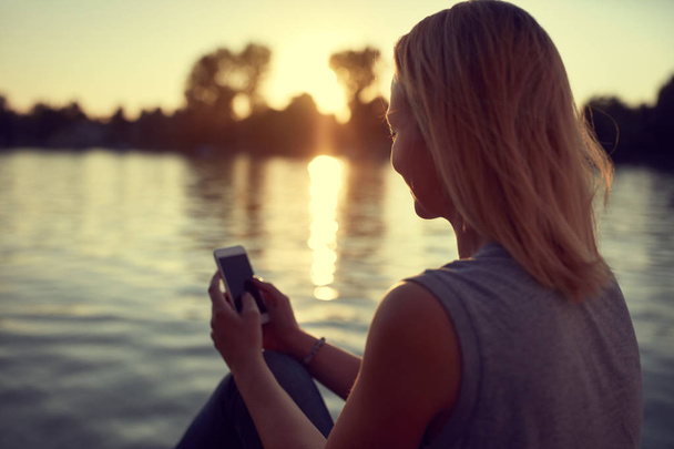 Woman near water with cellphone  - Zdjęcie, obraz