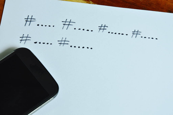  hashtag symboli sisällön ryhmittelyyn sosiaalisen median kirjoittaa paperille ja älypuhelimeen
 - Valokuva, kuva