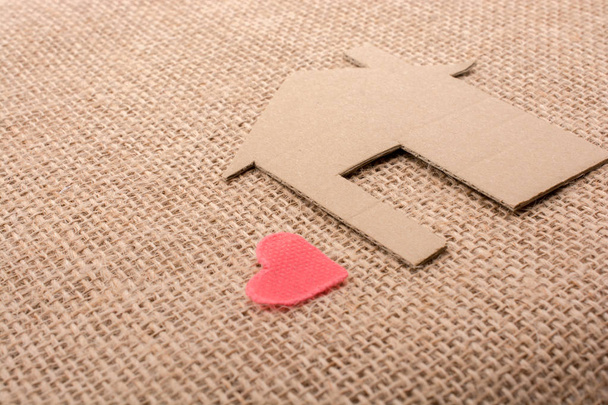 Coeur en forme à côté de la maison en papier avec un fond de toile
 - Photo, image