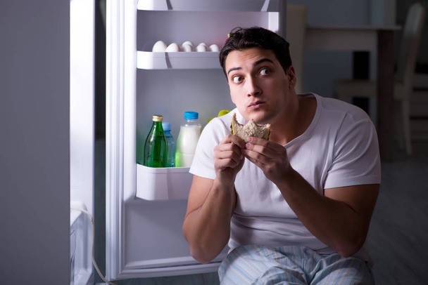 Az ember a hűtőben eszik éjszaka. - Fotó, kép