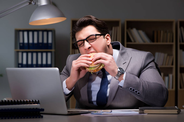 Egy üzletember késő este hamburgert eszik. - Fotó, kép