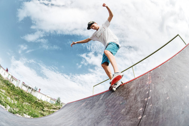 Teen skater hang up over a ramp on a skateboard in a skate park - Photo, Image