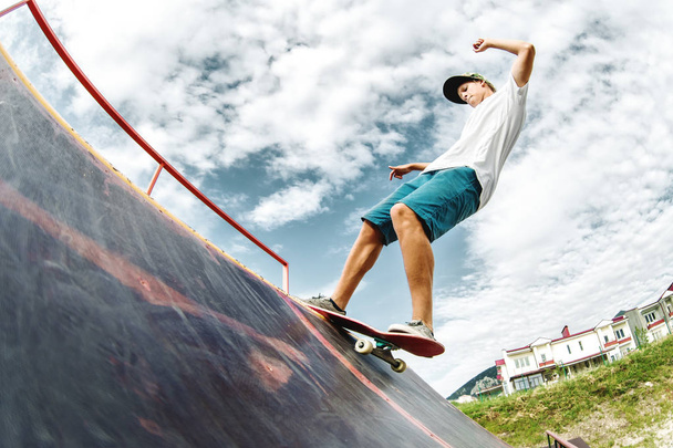 Teen skater hang up over a ramp on a skateboard in a skate park - 写真・画像