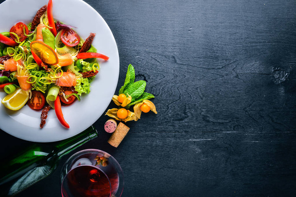 Salad with salmon and fresh vegetables and herbs. Italian cuisine. Top view. On Wooden background. - Foto, afbeelding