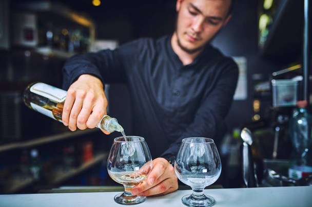Barman pouring hard spirit into glasses - Foto, afbeelding