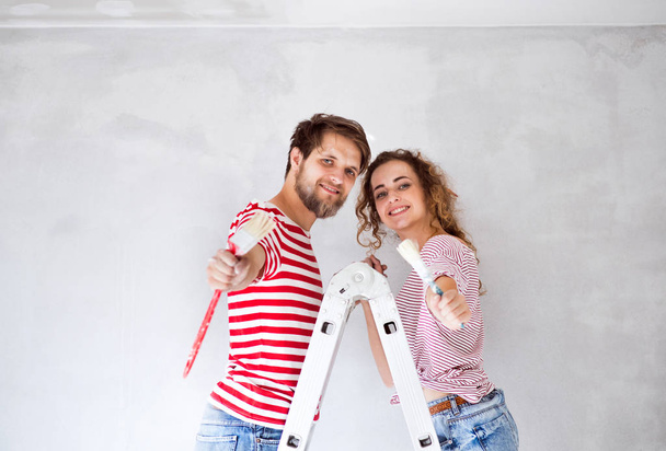 junges Paar streicht Wände in seinem neuen Haus. - Foto, Bild
