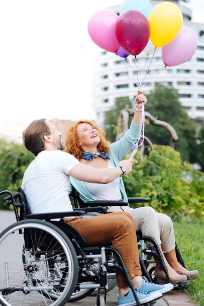 Cheerful senior disabled couple holding balloons - Foto, Imagen