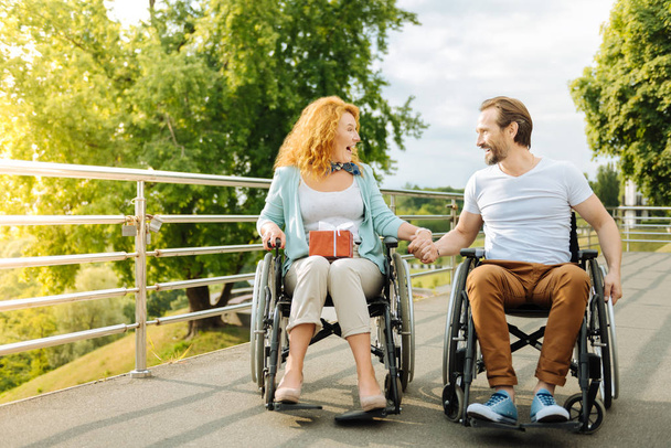 Emotional senior couple resting outdoors in the wheelchairs - Valokuva, kuva
