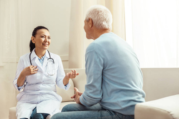 Delighted positive nurse talking to her patient - Foto, imagen