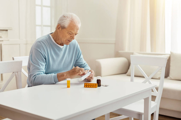 Nice elderly man holding a box with pills - 写真・画像