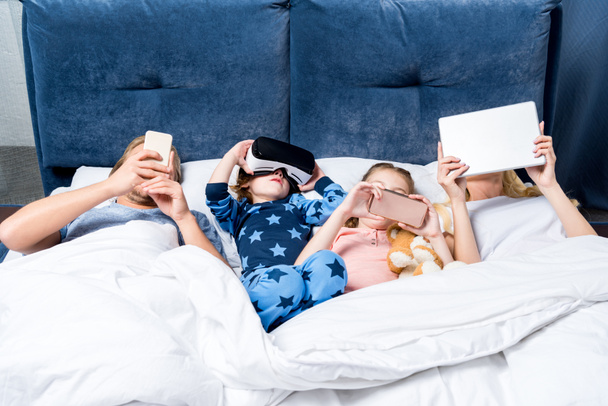 familia con aparatos en la cama
 - Foto, imagen