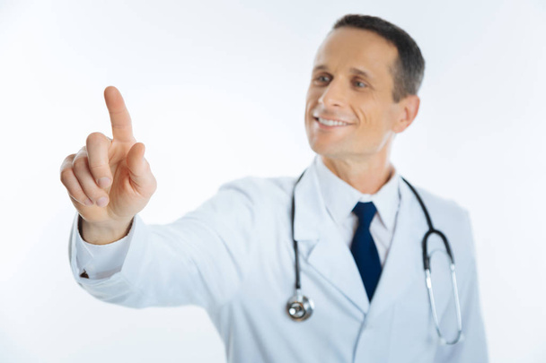 Cheerful medical professional pretending to touch invisible screen - Fotó, kép
