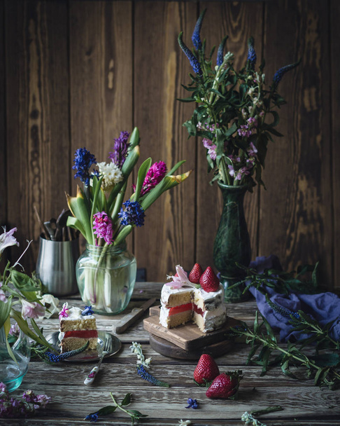 Ciasto z truskawkami i kwiat na drewnianym stole - Zdjęcie, obraz