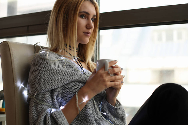 γυναίκα με ελαφριά γιρλάντα πίνοντας καφέ  - Φωτογραφία, εικόνα