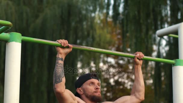 Muscular man doing pull-ups on horizontal bar - Filmati, video