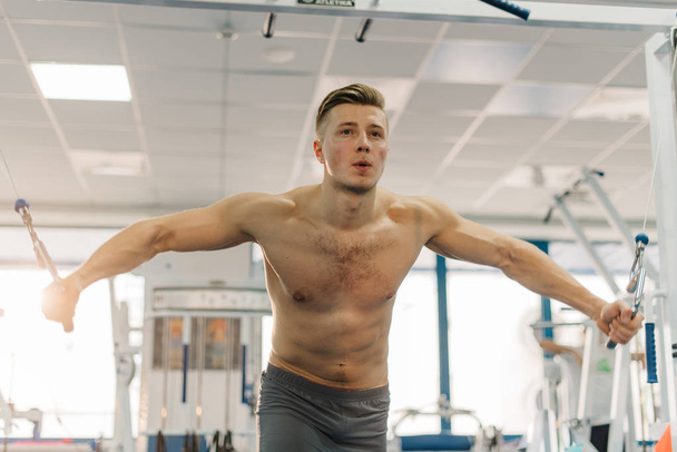 close up photo of beautiful man training on Fitness-station. Guy has strong hands. He working out to develop strength,develop definition of muscles - Valokuva, kuva