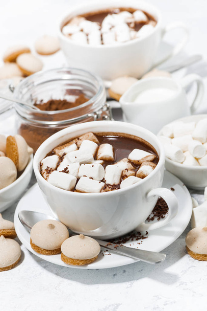 cups of hot chocolate with marshmallows on white table, vertical - Photo, Image