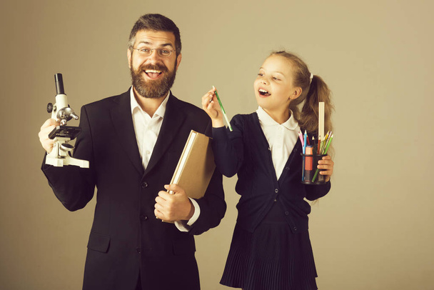 Teacher and schoolgirl with happy smiling faces on beige background - Photo, image