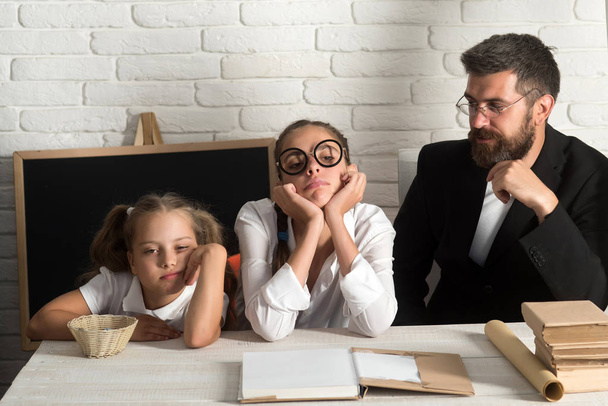Girls and bearded man sit at desk with books - Foto, afbeelding