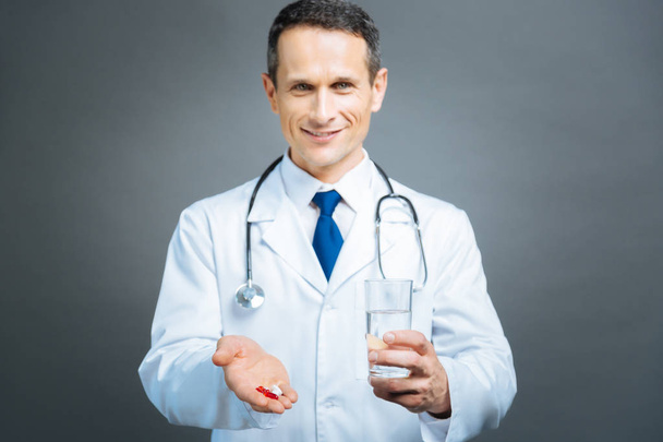 Mindful male doctor brining pills and water - Foto, imagen