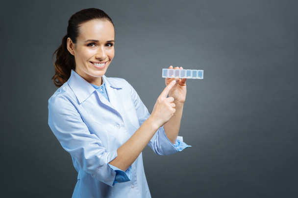 Radiant female practitioner posing with plastic box for pills - Zdjęcie, obraz