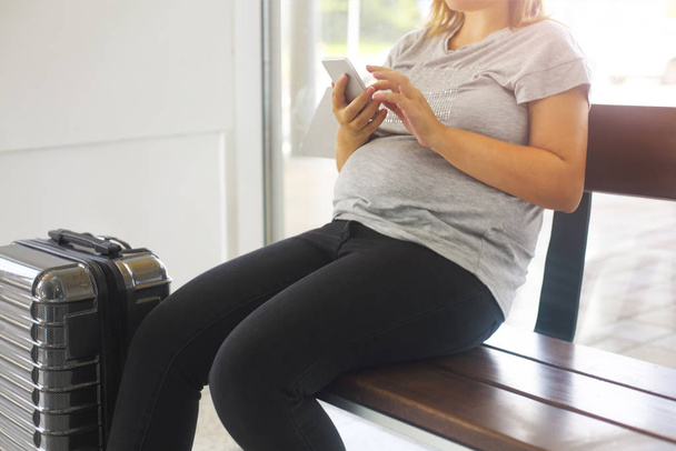 Jeune femme enceinte avec valise à l'aéroport
 - Photo, image