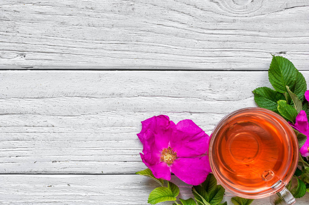 Чашка трав'яного рожевого хіп-чаю на білому дерев'яному фоні
 - Фото, зображення