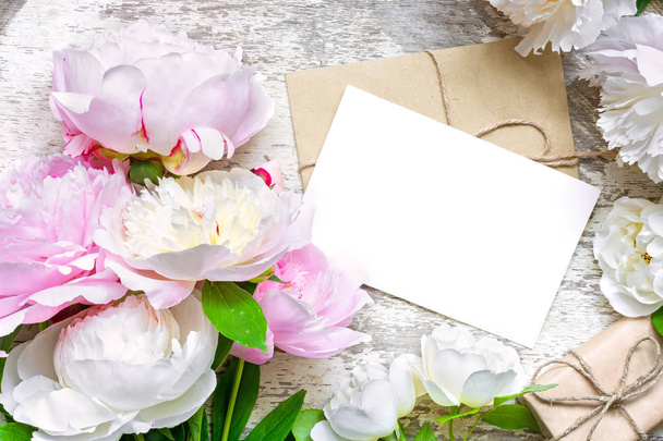 üres fehér üdvözlőlap és boríték ajándék doboz, a keret a pünkösdi rózsa és a rózsa virágok - Fotó, kép