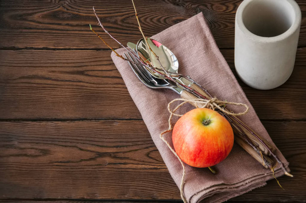 Tree branches, apple, cutlery on a linen sackcloth on a wooden b - Foto, imagen