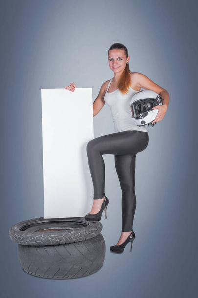 Beautiful young woman with tire in studio on gray background - Valokuva, kuva
