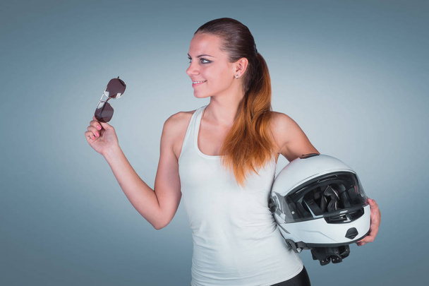 Beautiful young woman with moto helmet in studio on blue backgro - Foto, afbeelding